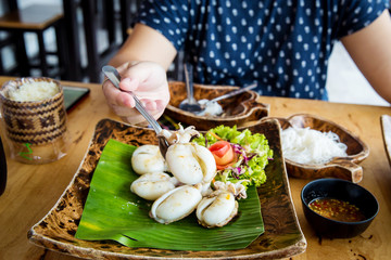 fried squids in wood plate.Steamed squid fried with salty sauce Thai food.Grilled squid and vegetable with spicy seafood sauce on wood table.