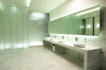 mirror, basins and faucets in cozy public restroom
