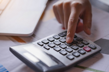 Close up hand of businesswoman or accountant working on calculator to calculate business data, and accountancy document. Business financial and accounting concept.
