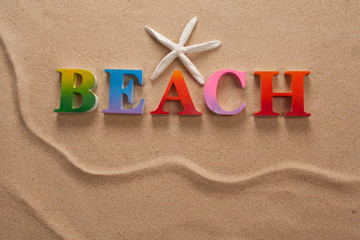 Fototapeta na wymiar top view of beach written in colorful letters decorate with shellfish on the beach with copy space