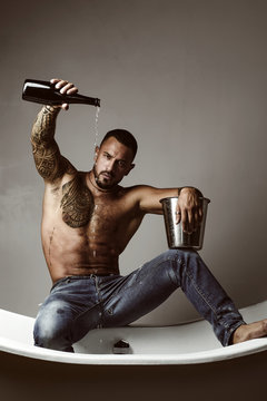 Champagne or wine celebration. Wine festival concept. Handsome man with tattooed body. Handsome brutal man on gray background. Mude male model with naked body.