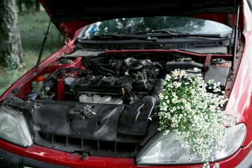 bouquet of flowers under the hood of a broken car