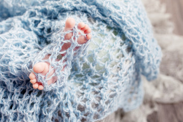 Newborn baby feet on knitted plaid. Closeup picture