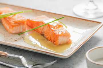 The beautiful serving of cooked fried salmon steak on a ceramic plate at a restaurant.