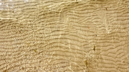 River yellow sand, lying in waves at the bottom of the river