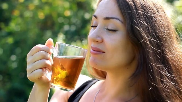 Young woman is drinking tea with mint outdoor.