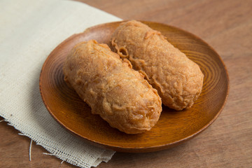 Fried bananas in wooden plate on white linen, Kluay Tod - Thai dessert.