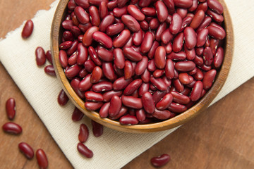 Red beans in wooden bowl putting on linen and wooden background.