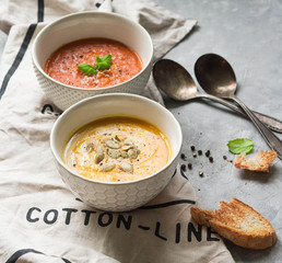 Homemade autumn soups -  pumpkin cream-soup and tomato cream soup on a linen towel on a gray background
