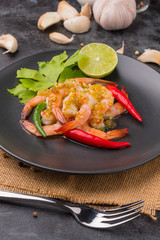 Shrimps topped with seafood sauce on black dish.
