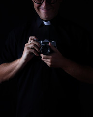 smiling priest with the camera