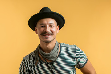 Portrait of modern handsome craftsman with moustache wearing creative hat, neck scarf, bracelets,...