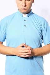 young priest is praying in a blue shirt
