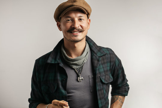 Portrait of a cheerful craftsman selling online self made leather goods via smartphone, isolated over white background with copyspace. Small business and leather goods manufacturing