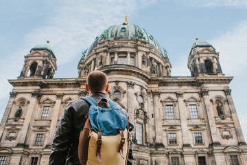 A tourist or traveler with a backpack looks at a tourist attraction in Berlin called Berliner Dom. Traveling in Germany. © franz12