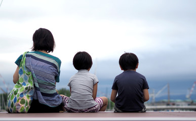 Behind images of family sitting in front of the harbor port or sea dock in Otaru Hokkaido Japan which includes such as father mother daughter and son on the wood pier.