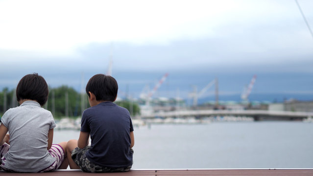 Behind images of family sitting in front of the harbor port or sea dock in Otaru Hokkaido Japan which includes such as father mother daughter and son on the wood pier.