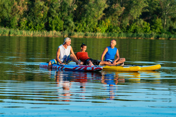 Happy friends, a SUP surfers relax on the big river