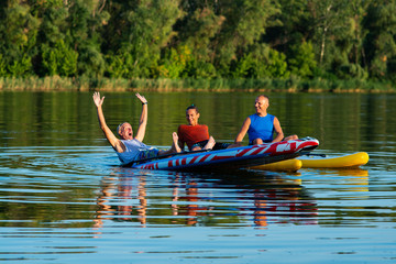Fototapeta na wymiar Happy friends, a SUP surfers relax on the big river during sunset