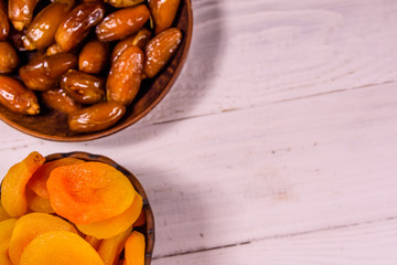 Date fruits and dried apricots on wooden table. Top view