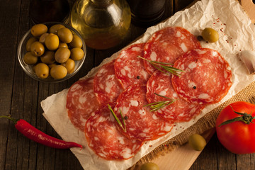 Chorizo sausage and salami, thin cut. spanish salami on the wood background with spices, paprika, pepper. Spicy food. Garlic, tomato, salad background.