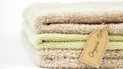 Fototapeta na wymiar Pile of organic cotton bath towels on white background. Eco textile tag.