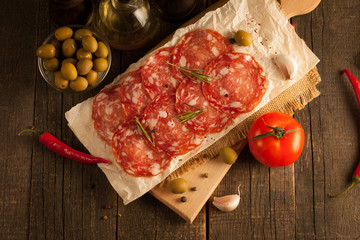 Chorizo sausage and salami, thin cut. spanish salami on the wood background with spices, paprika, pepper. Spicy food. Garlic, tomato, salad background.