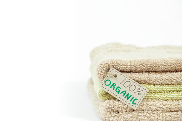 Fototapeta na wymiar Pile of organic cotton bath towels on white background. Eco textile tag. Blank copy space for text.