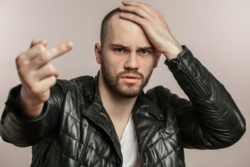 male in stylish leather jacket touching his head and showing dislike gesture. isolated white...