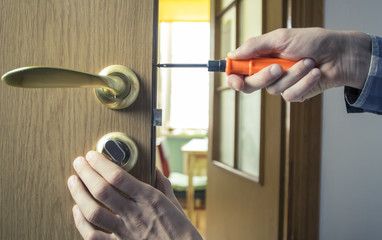 Hands repair the door lock.
