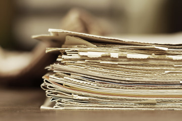 Old newspapers with yellow pages stacked in pile, stack of tabloid news journals, side view 