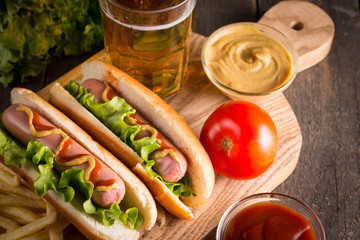 Photo of barbecue grilled hot dog with yellow mustard and ketchup on wooden background. Hot dog...
