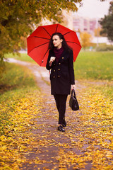 Obraz premium a girl walks in the autumn park under an umbrella