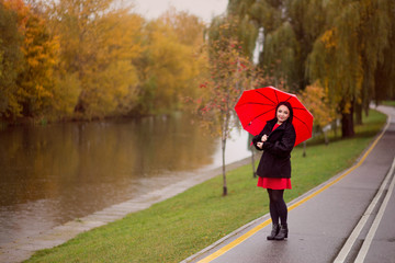 a girl walks in the autumn park under an umbrella