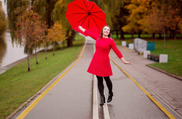 happy girl walks in the autumn park under an umbrella