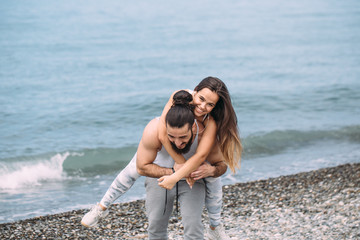 Playful sportive men giving piggyback ride to women on beach. young people having fun on the beach...