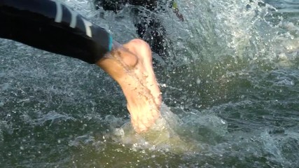 athletes changing race discipline from swimming to biking on river slow motion. open water triathlon distance ironman triathlon competition. Healthy lifestyle. Wellness, sport and fitness concept