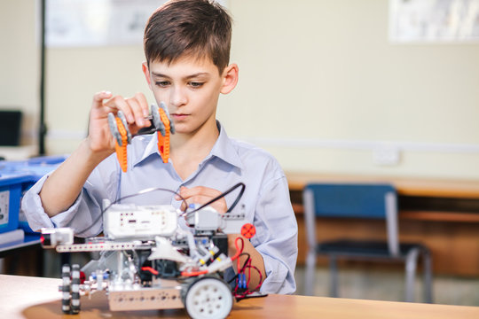 Little boy in robotics school makes robot managed from the constructor, child learns robot constructing.