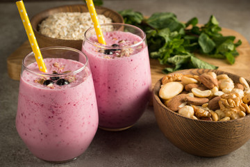 Glasses of berry smoothie with nuts, mint, blueberry, blackberry, raspberry, and yogurt on wooden table. Weight loss and diet concept. 
