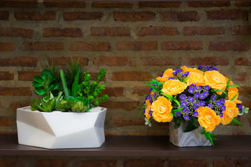 Flower bouquet with beautiful orange, purple flowers artificial and succulent cactus on wooden table and brick wall in background