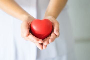 Female nurse holding a red heart shape. Health care insurance and love concept