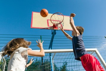 Streetball basketball game with two players, teenagers girl and boy, morning on basketball court.