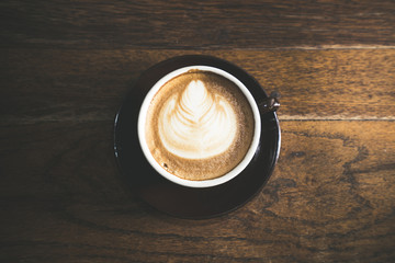 Closeup latte art of coffee brown cup on wooden table surface