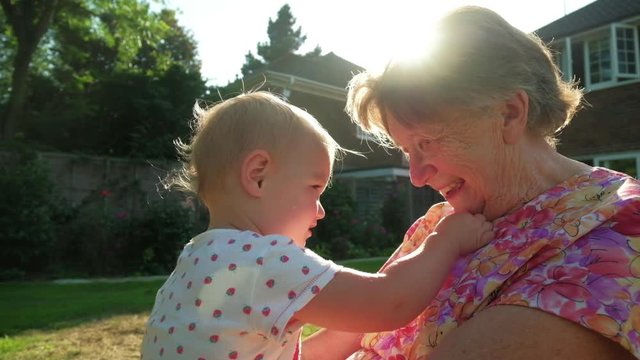 Portrait of a senior caucasian woman with her grand daughter in her garden backlit by the sun