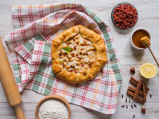 Apple pie with Goji berries on a white wooden table. Rustic style.

