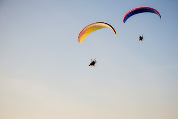 Adventure man active extreme sport pilot flying in sky with paramotor engine glider parachute. Paramotor flying on the sky at sunset. 