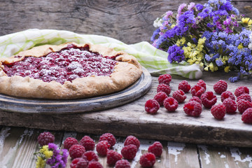 Sweet delicious freshly baked homemade French Country Pie with raspberries on a wooden table with...