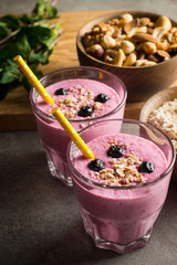 Glasses of berry smoothie with nuts, mint, blueberry, blackberry, raspberry, and yogurt on wooden table. Weight loss and diet concept. 