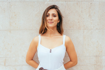 Smiling friendly woman standing against a wall