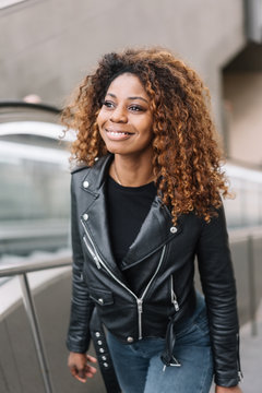 Young black smiling woman going up escalator